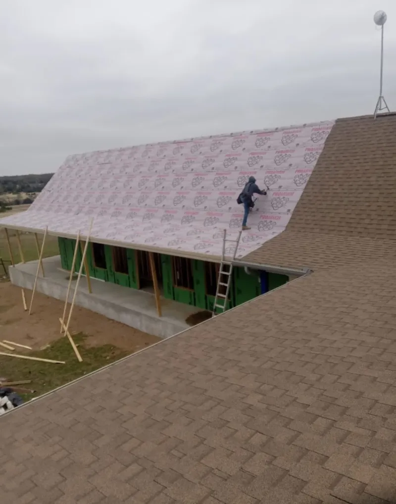 Worker preparing underlayment for a metal roof installation in Two Rivers